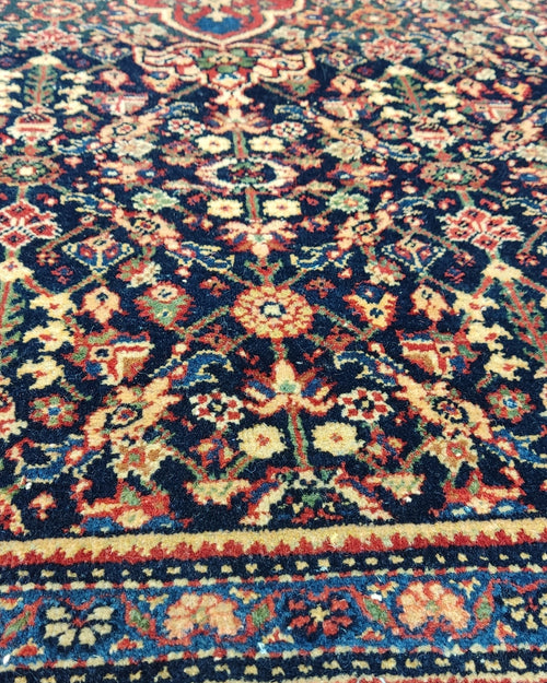 Tappeto Farahan antico persiano annodato a mano con medaglione centrale e ricchi motivi floreali su fondo blu notte, misura 203x130 cm