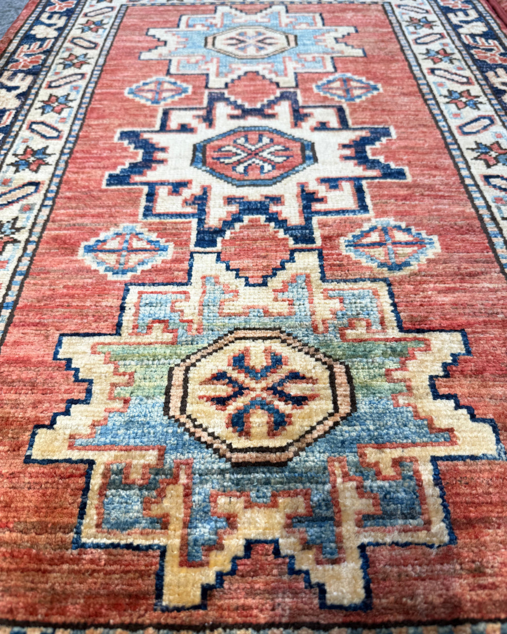 Kazak 100x63 cm, coppia di scendiletto con medaglioni geometrici su fondo rosso mattone