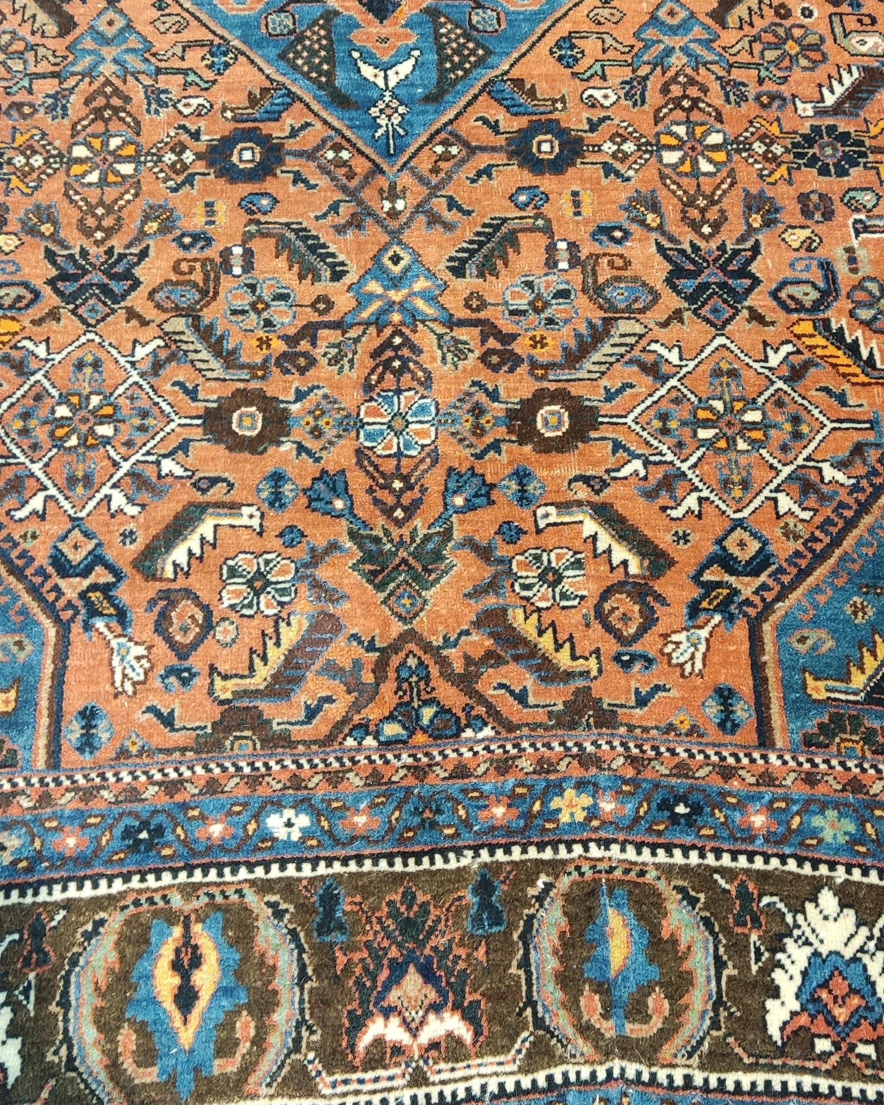 Tappeto Qashqai persiano annodato a mano con medaglione centrale azzurro e motivi tribali su fondo terracotta, misura 162x112 cm