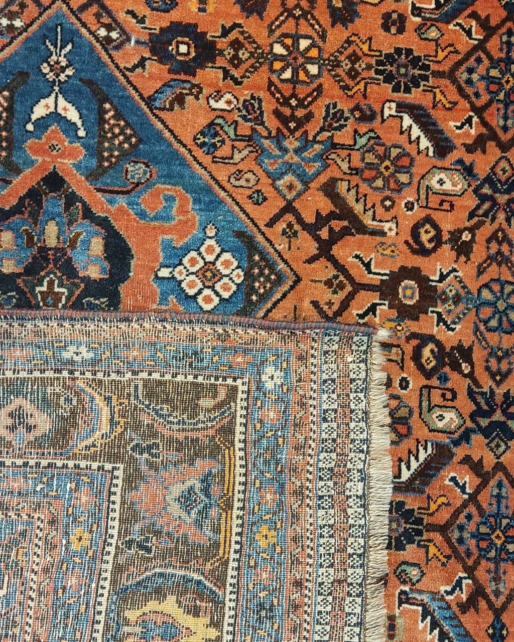 Tappeto Qashqai persiano annodato a mano con medaglione centrale azzurro e motivi tribali su fondo terracotta, misura 162x112 cm