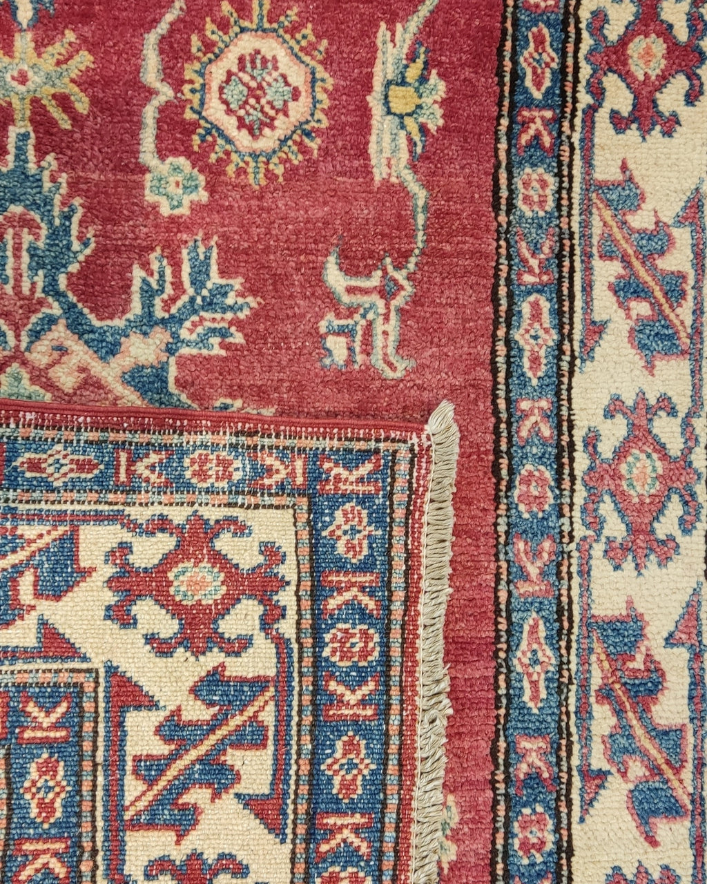 Tappeto Uzbek annodato a mano con fondo rosso rubino e motivi geometrici caucasici nei toni dell'avorio e dell'azzurro, misura 158x108 cm